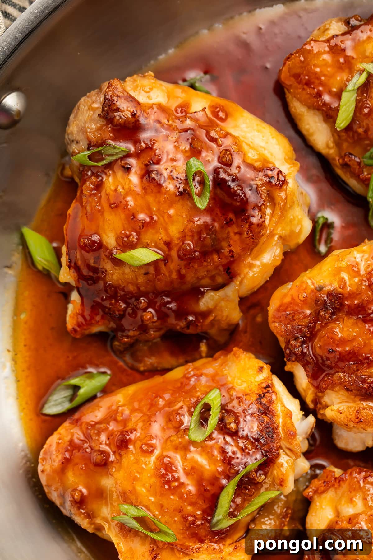 Sticky Sweet Honey Garlic Chicken 3 Honey garlic chicken thighs, seared and then roasted until crisp, resting in a silver skillet with additional sauce.