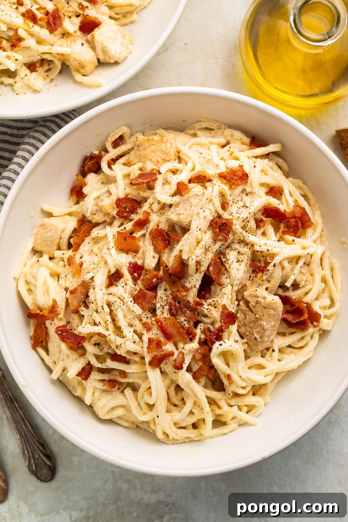 A large white bowl of paleo carbonara made with palmini, dairy-free Alfredo sauce, and compatible bacon, garnished with fresh parsley.