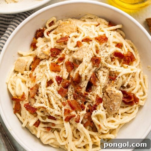 A large white bowl of paleo carbonara made with palmini, dairy-free Alfredo sauce, and compatible bacon.