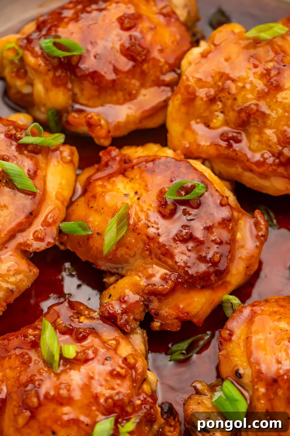 Sriracha Honey Glazed Chicken 3 Honey sriracha chicken thighs resting in a large silver skillet with honey sriracha sauce.