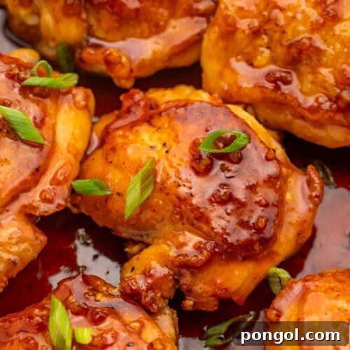 Sriracha Honey Glazed Chicken 4 Honey sriracha chicken thighs resting in a large silver skillet with honey sriracha sauce.