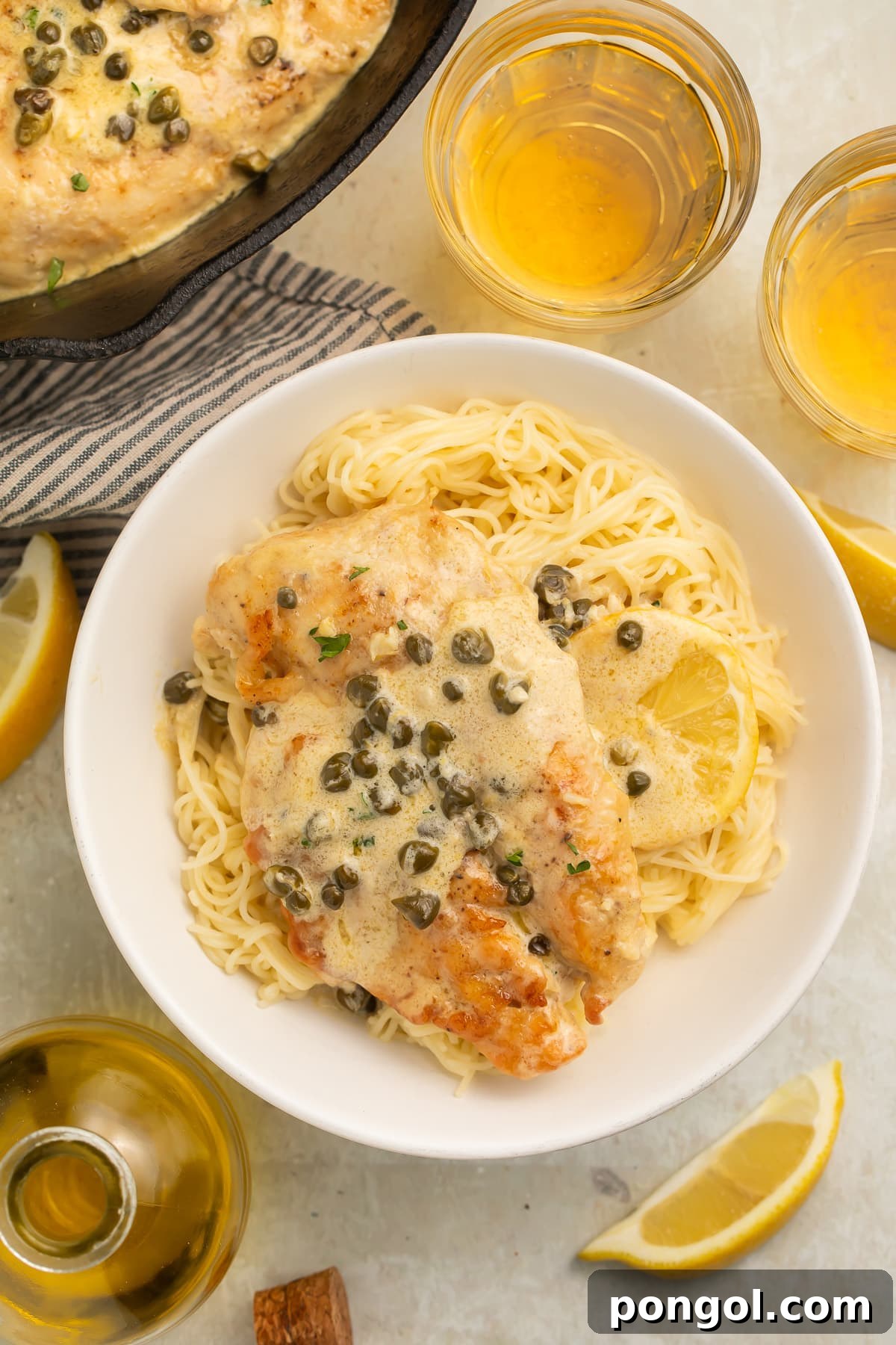 Chicken piccata plated with pasta and capers.
