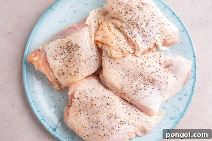 Flavorful One-Pan Chicken Dinner 7 Chicken thighs seasoned with salt and pepper on a large round plate.