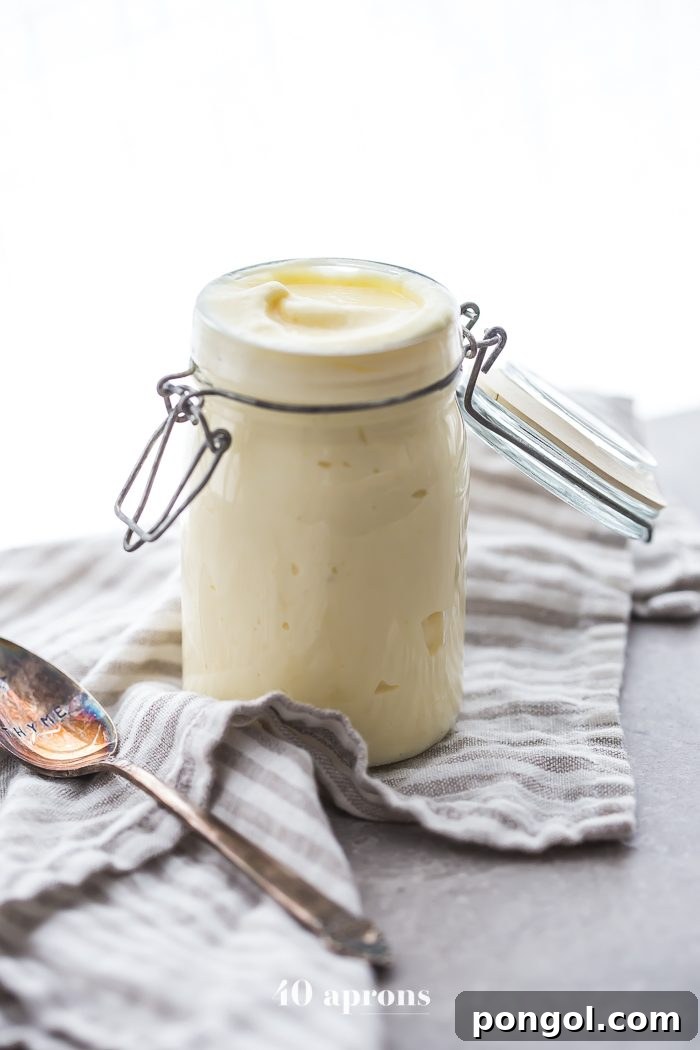 Close-up of creamy Whole30 mayonnaise in a glass jar, showing its thick texture.