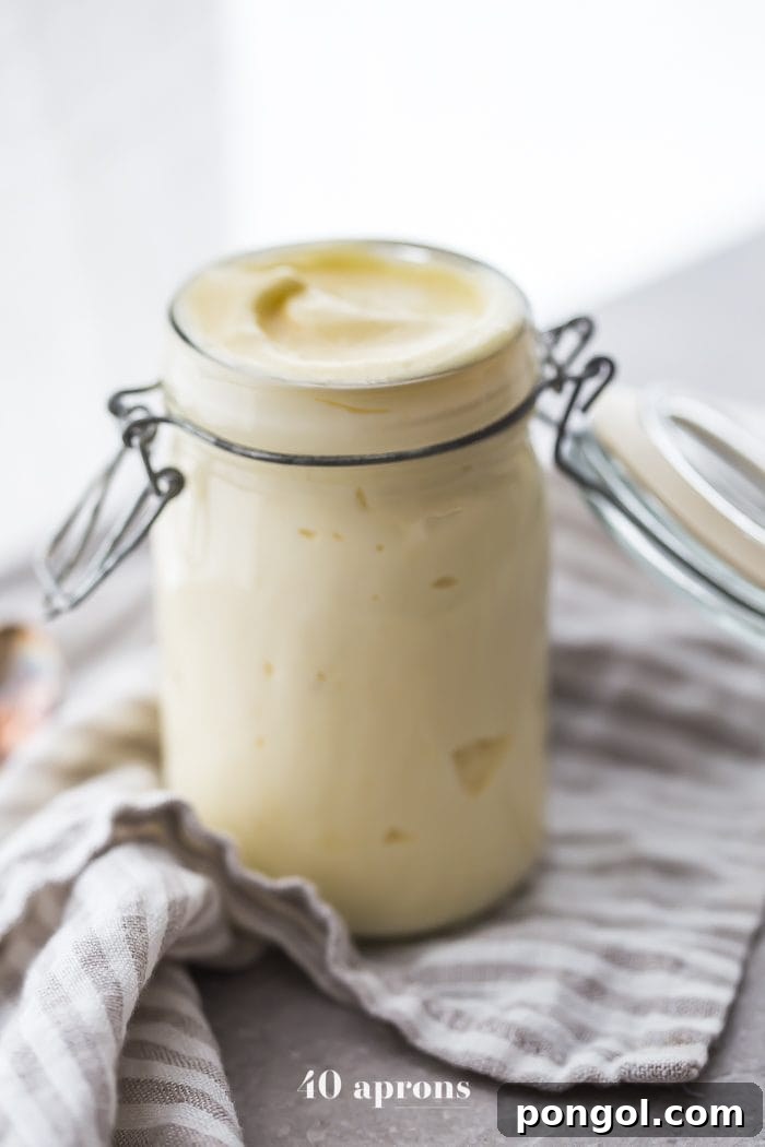 An immersion blender actively emulsifying ingredients to make Whole30 mayonnaise in a jar.