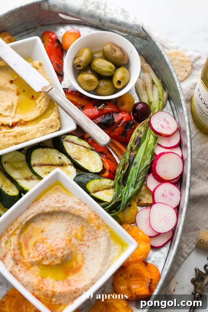 A section of the healthy Greek appetizer platter featuring grilled apricots, fresh fruits, nuts, and a block of feta with cherry reduction