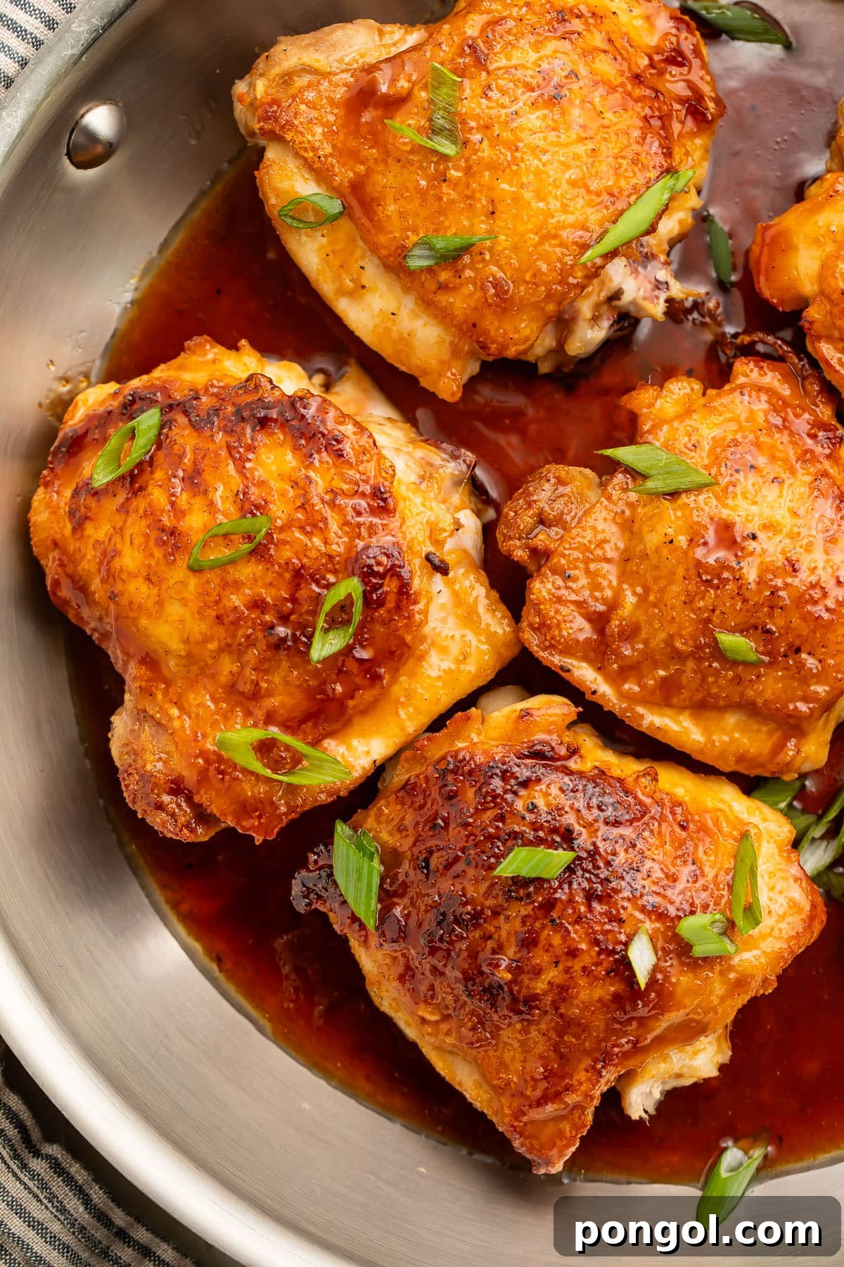 One-Pan Hot Honey Chicken 2 4 of 6 bone-in, skin-on chicken thighs in a large silver skillet with a hot honey sauce.