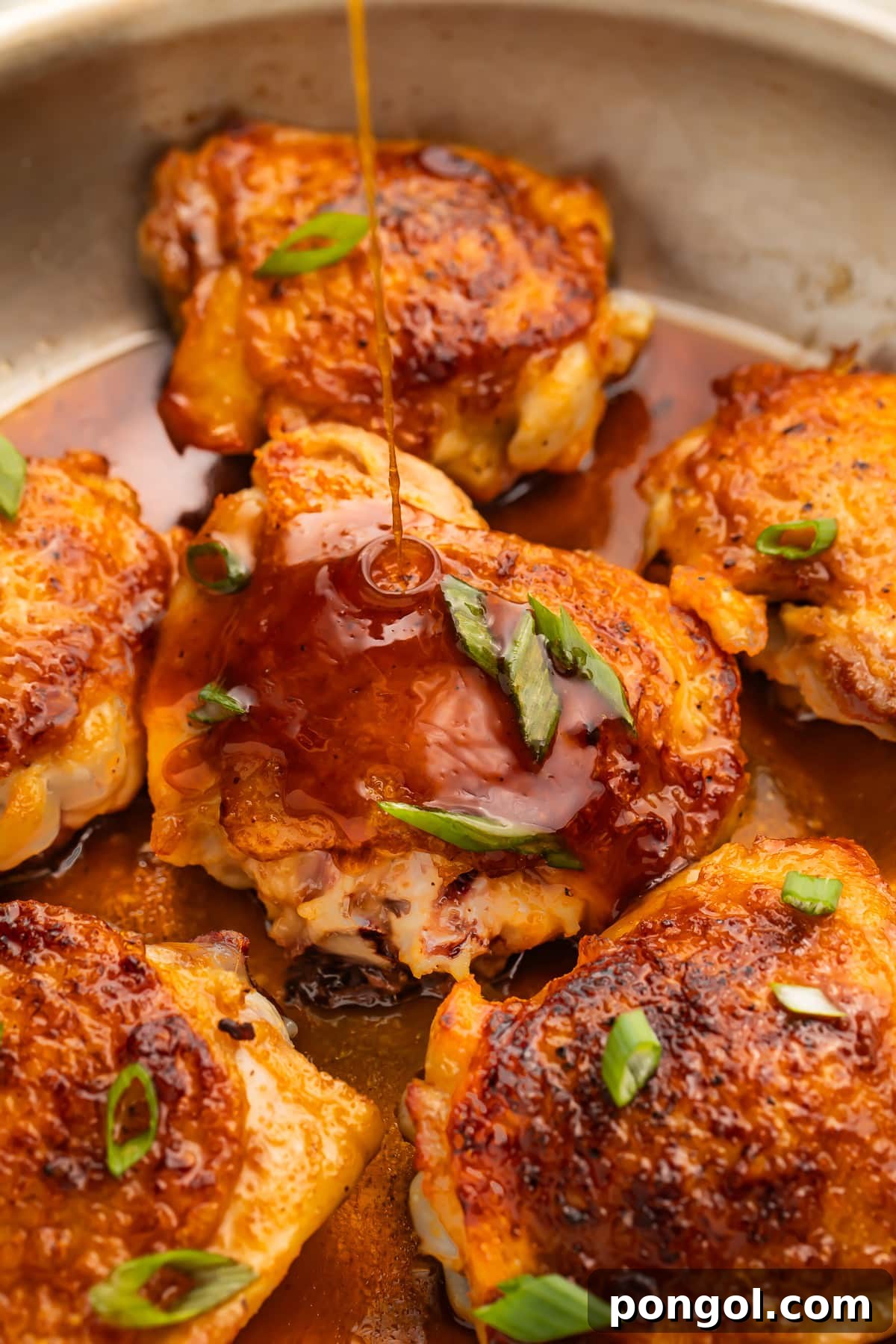 One-Pan Hot Honey Chicken 3 Hot honey sauce being poured over crispy chicken thighs in a large silver skillet.