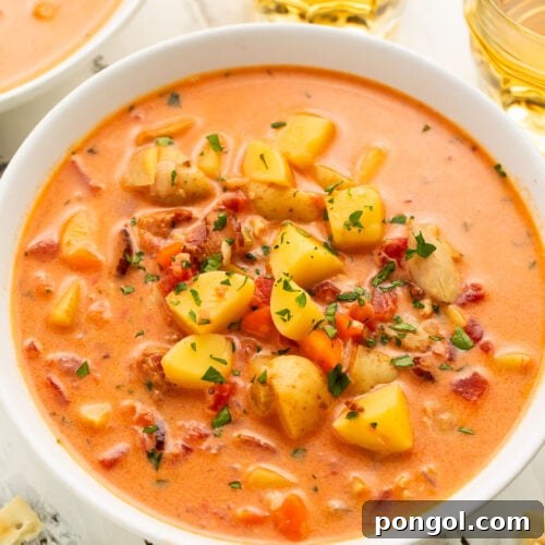 Overhead view of Manhattan clam chowder in a large white soup bowl with chunks of diced potatoes and chopped clams.