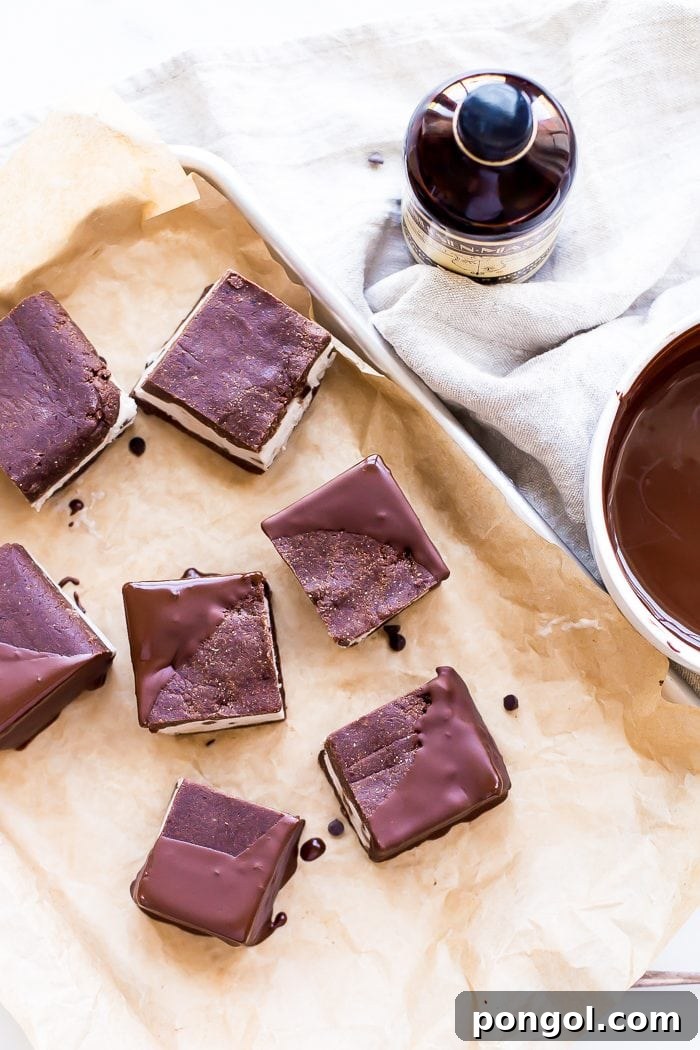 Several chocolate-dipped healthy vegan ice cream sandwiches arranged on parchment paper.