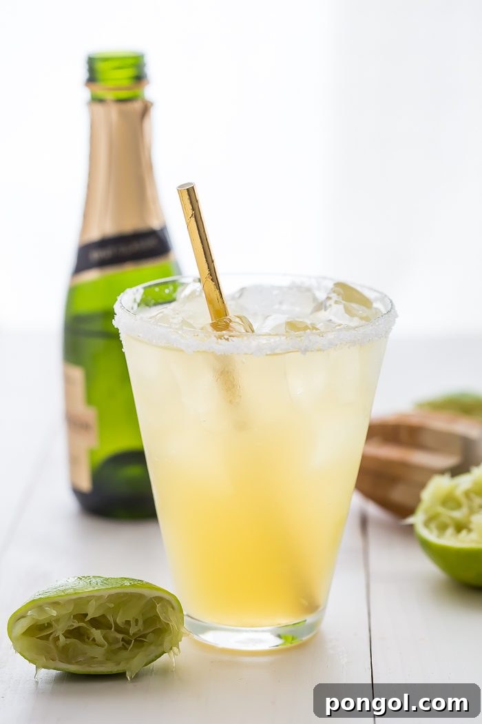 A close-up of the champagne bottle being poured into a margarita, showing the bubbly effect.