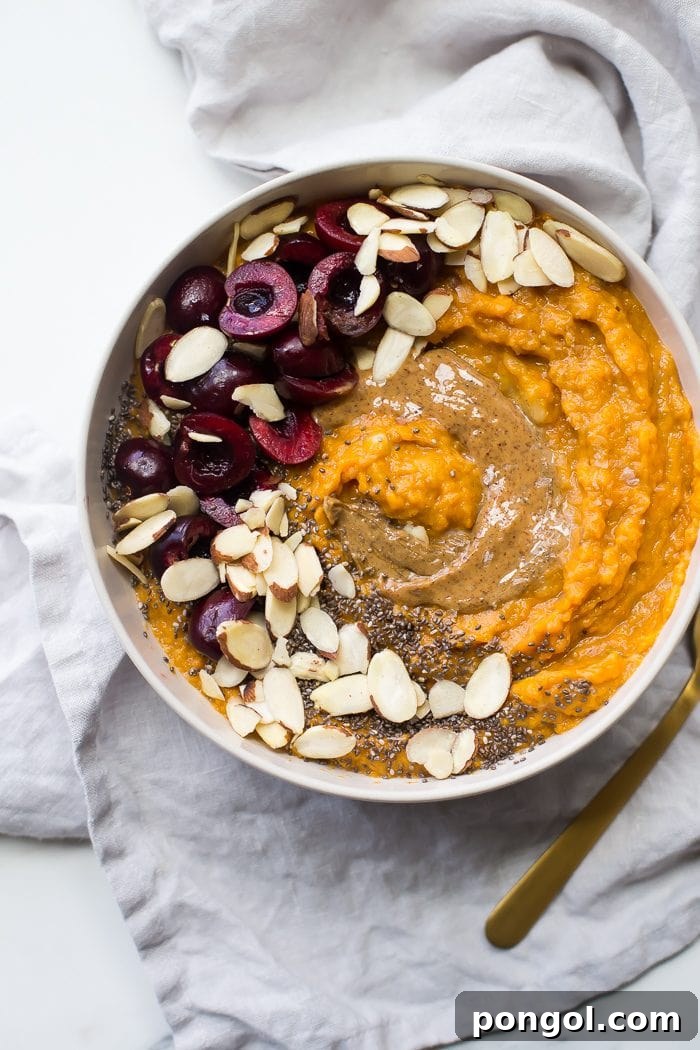 A close-up of a meticulously prepared sweet potato Whole30 breakfast bowl, showcasing its creamy texture and an assortment of wholesome toppings. The golden-orange hue of the sweet potato contrasts beautifully with the vibrant fruit and nuts, highlighting its appeal as a nutritious and delicious Whole30 compliant meal.