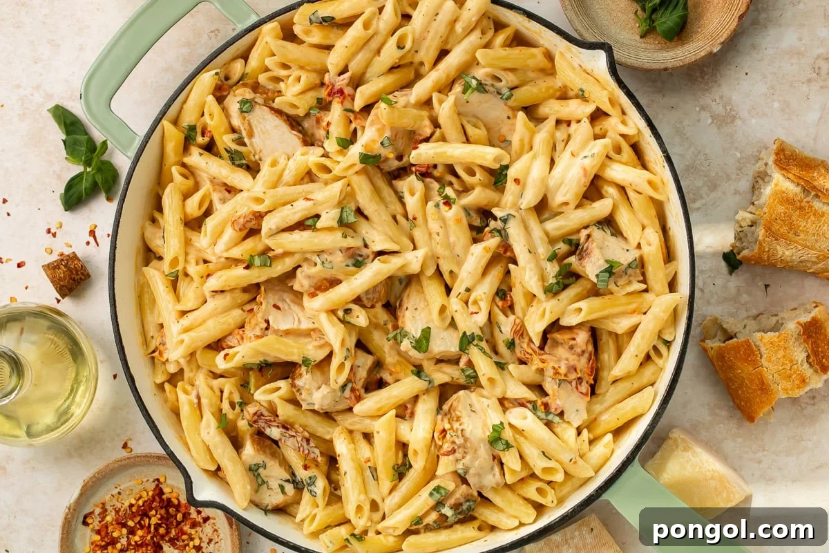 Bowl of marry me chicken pasta garnished with fresh basil and parmesan cheese on dinner table