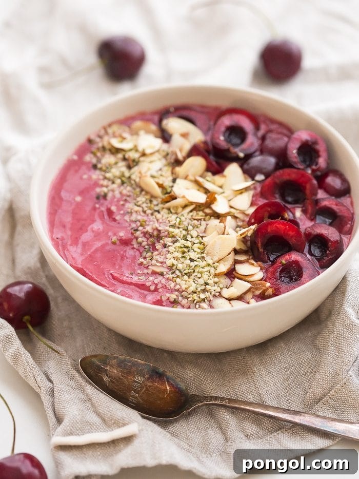 Close-up of a creamy cherry smoothie bowl topped with fresh cherries and nuts.
