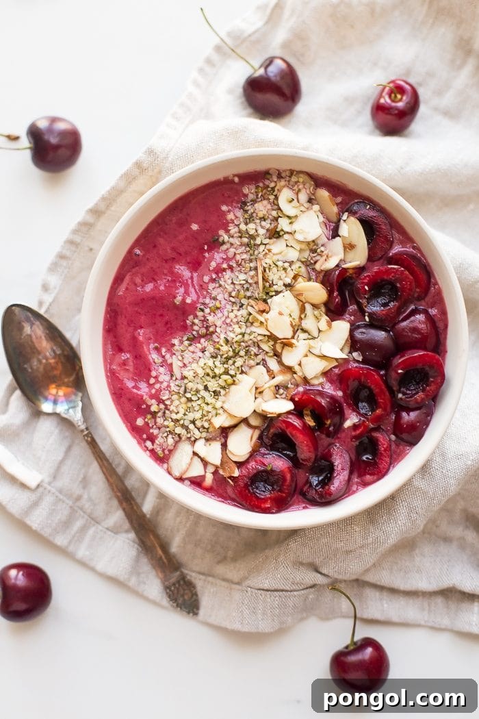Ingredients for a healthy and refreshing cherry smoothie bowl laid out on a table.