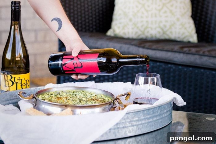 Creamy Paleo Vegan Spinach Artichoke Dip 6 A bowl of paleo spinach artichoke dip with a single chip dipped in it