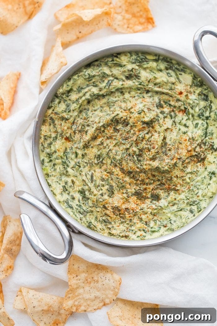 Paleo spinach artichoke dip garnished with paprika and served with vegetable sticks