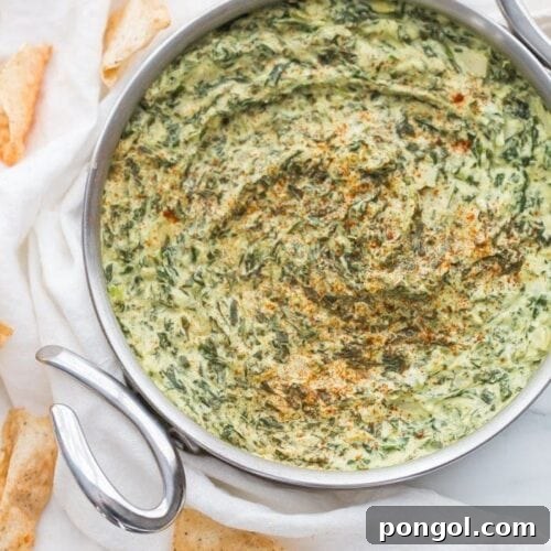 Creamy Paleo Vegan Spinach Artichoke Dip 10 Paleo Spinach Artichoke Dip in a bowl, garnished with herbs and served with dippers