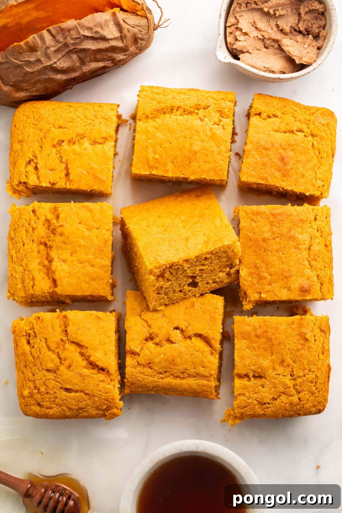 A neatly arranged 3x3 grid of sweet potato cornbread squares, showcasing their golden crust and perfect portioning.