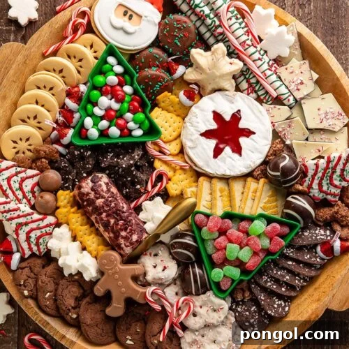 A Christmas dessert themed grazing board, packed full with Christmas tree cakes, brie, goat cheese, crackers, pretzels, truffles, nuts, cookies, and other holiday-themed treats.