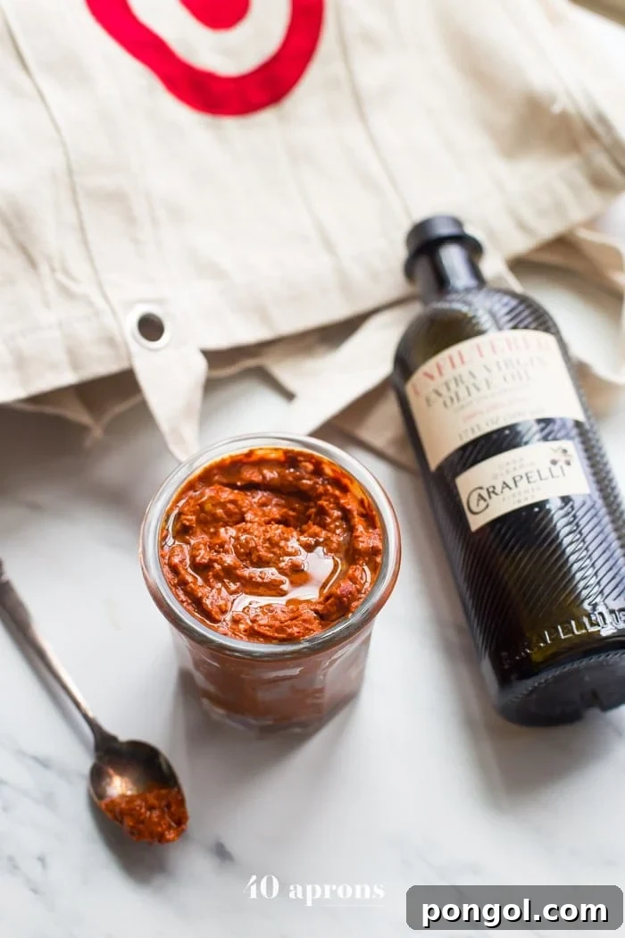 Overhead shot of a small side dish of homemade harissa spice paste next to a bottle of premium olive oil, ready to be served