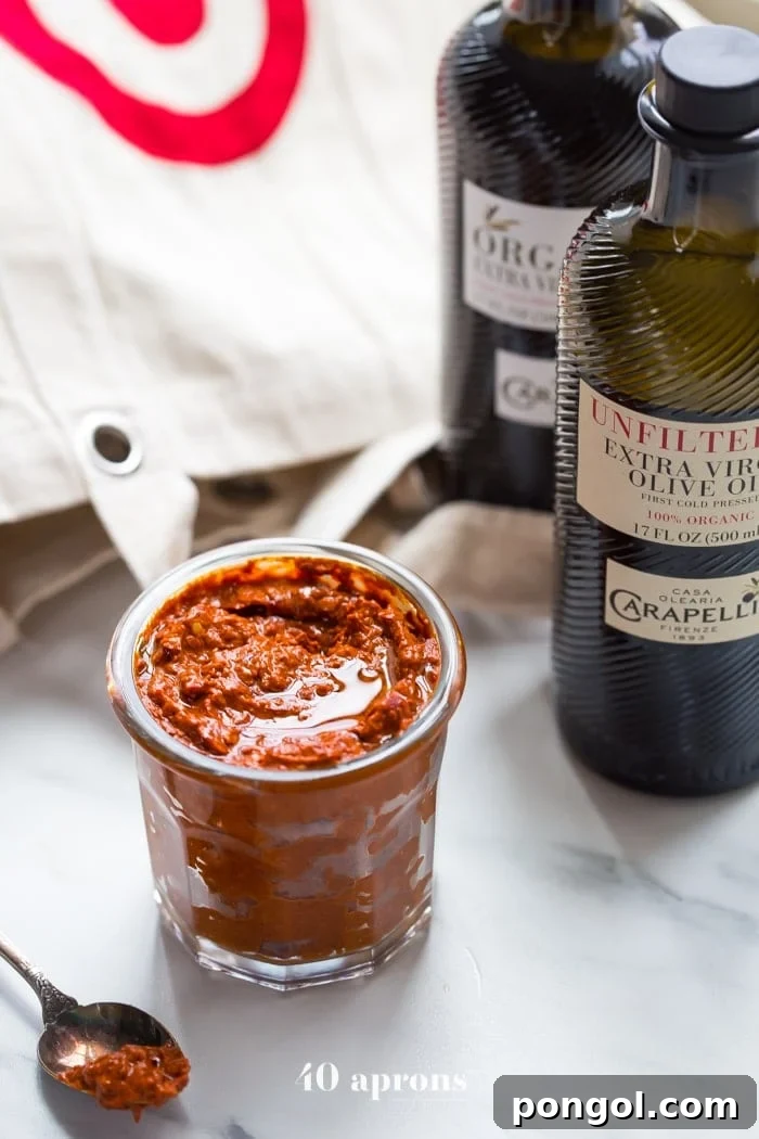 A small glass dish of homemade harissa spice paste placed elegantly next to a bottle of premium olive oil, emphasizing the quality ingredients