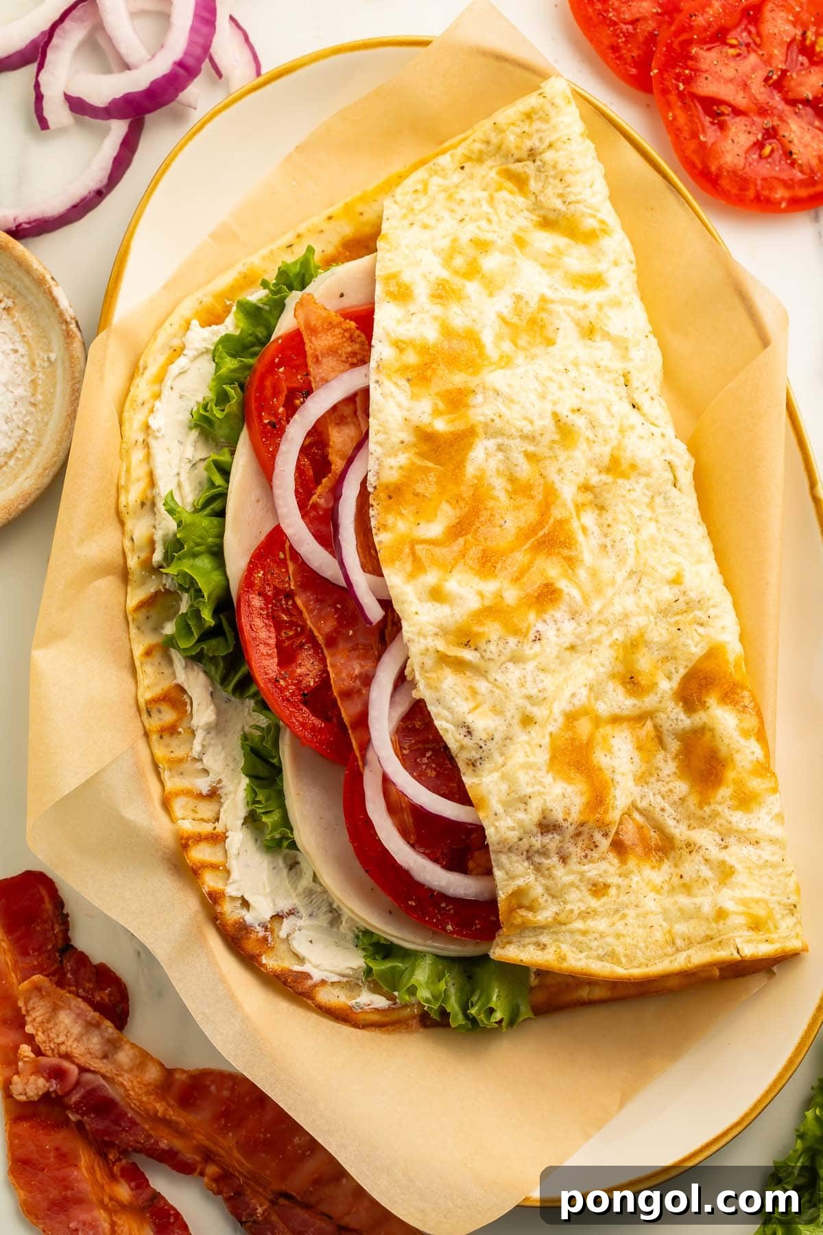 Creamy Cottage Cheese Flatbread Sensation 3 A perfectly folded flatbread sandwich, showcasing a generous filling of ham, bacon, fresh tomato, crisp lettuce, and sliced onion, all nestled within the wholesome cottage cheese flatbread.