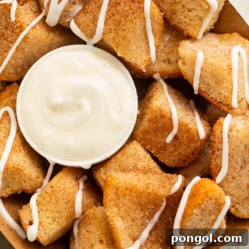 Close-up of a cardboard tray holding keto cinnamon roll bites (made from keto buns) with a cream cheese icing, ready to be enjoyed.