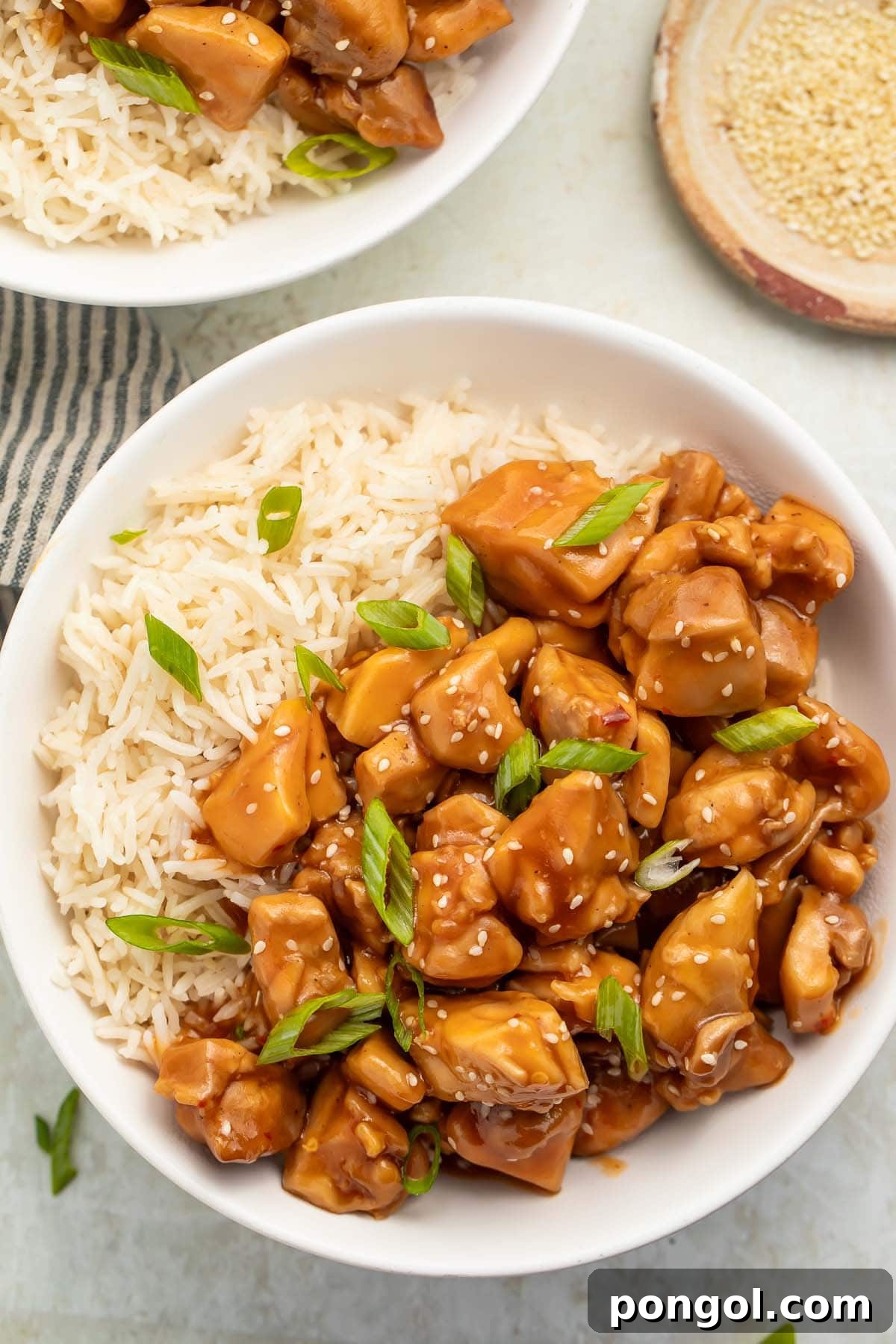 Mouthwatering Instant Pot Bourbon Chicken 2 Overhead photo of a bowl of Instant Pot bourbon chicken with white rice garnished with sliced green onions.