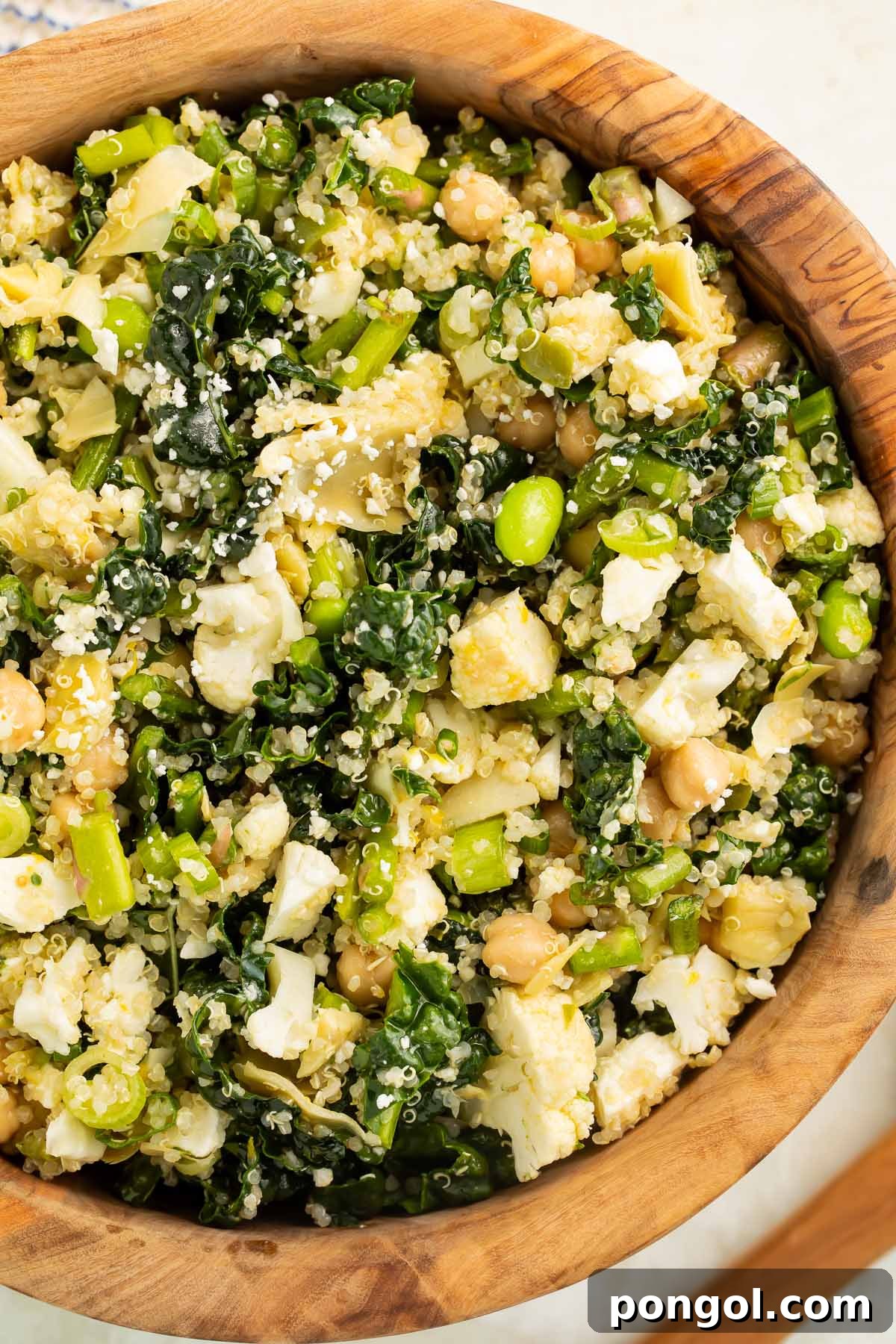 A close-up of a vibrant, fresh detox salad bowl, showcasing chickpeas, fluffy quinoa, crumbled feta cheese, and a colorful mix of vegetables.