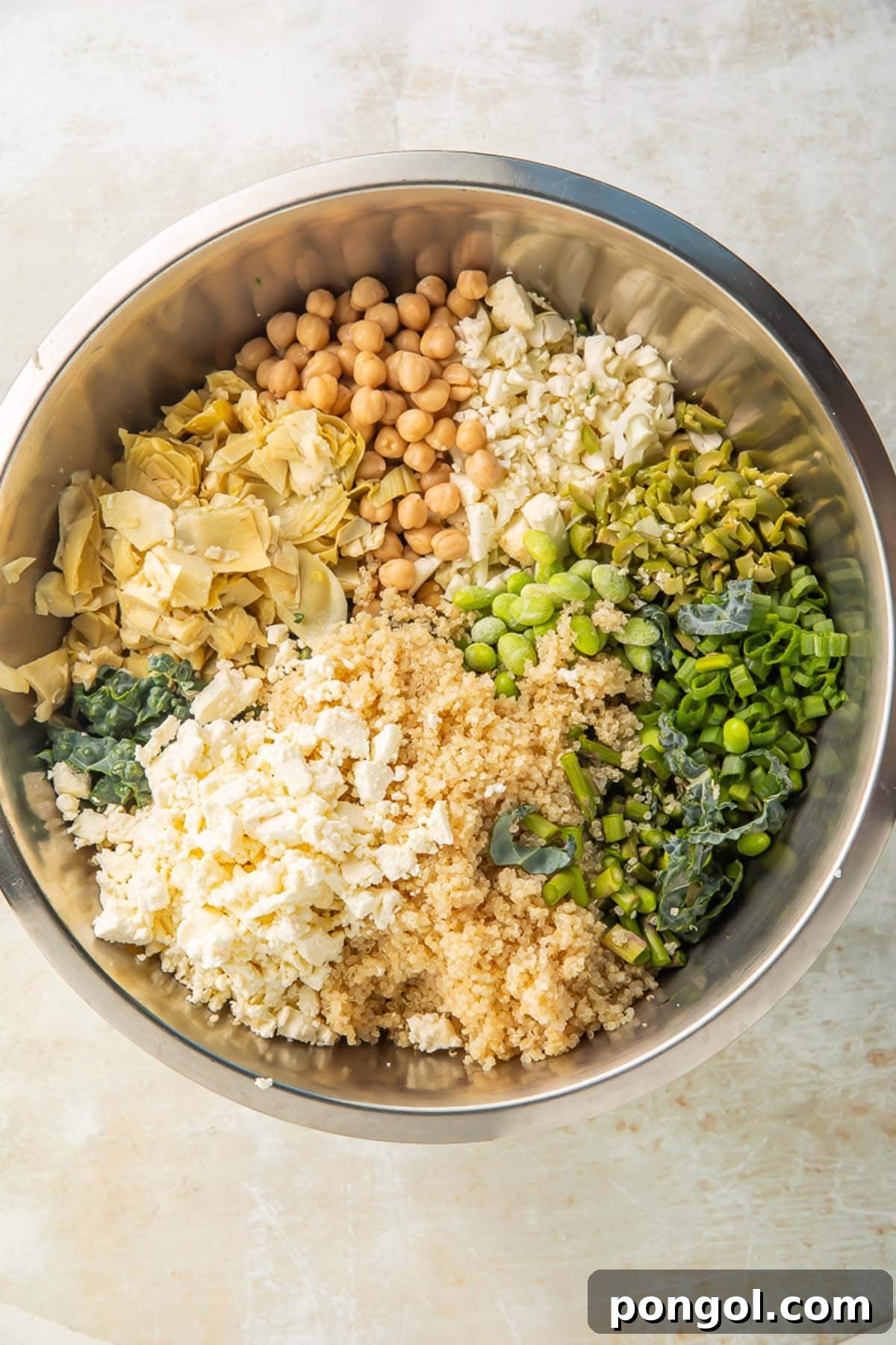 All the fresh ingredients for the detox salad, including quinoa, chickpeas, kale, and vegetables, gathered in a large mixing bowl, ready to be tossed.