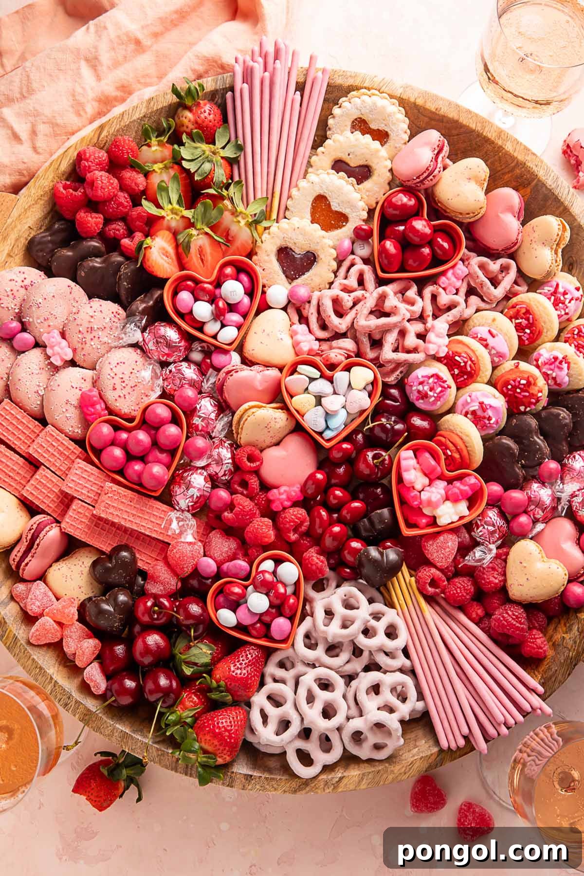 Cupid's Sweetest Board 2 A Valentine's Day themed charcuterie board filled with pink, red, and white cookies, candies, pretzels, fruits, and chocolates, ready for a romantic celebration.