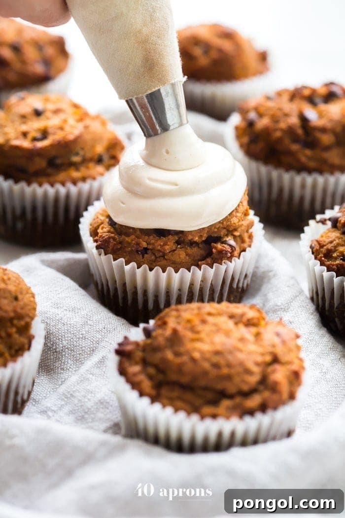 Close-up of a single Paleo Pumpkin Chocolate Chip Muffin, revealing melted dairy-free chocolate chips and a vibrant orange hue.