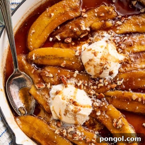 Rich bananas foster topped with scoops of vanilla ice cream in a large pan.