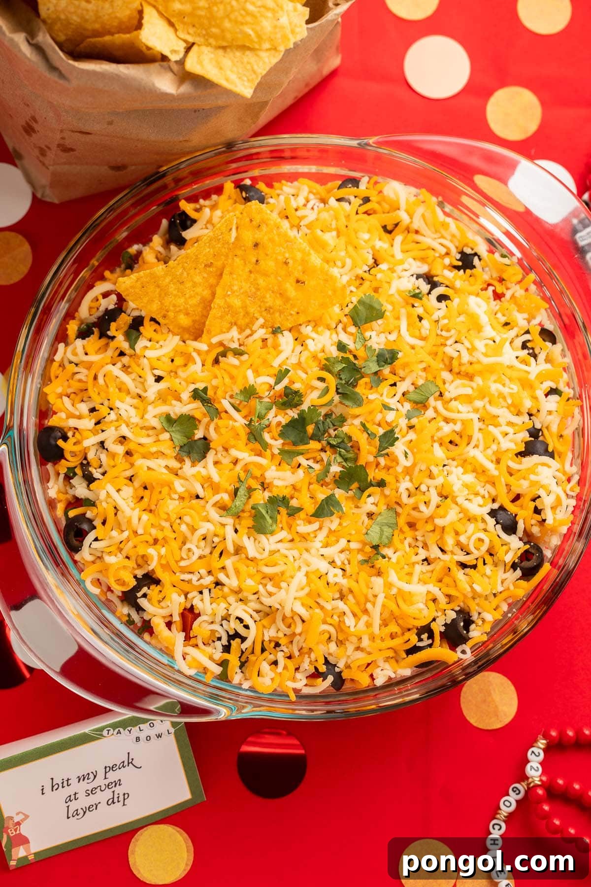 Marry me 7-layer dip in a large glass bowl, a colorful and tempting dish.