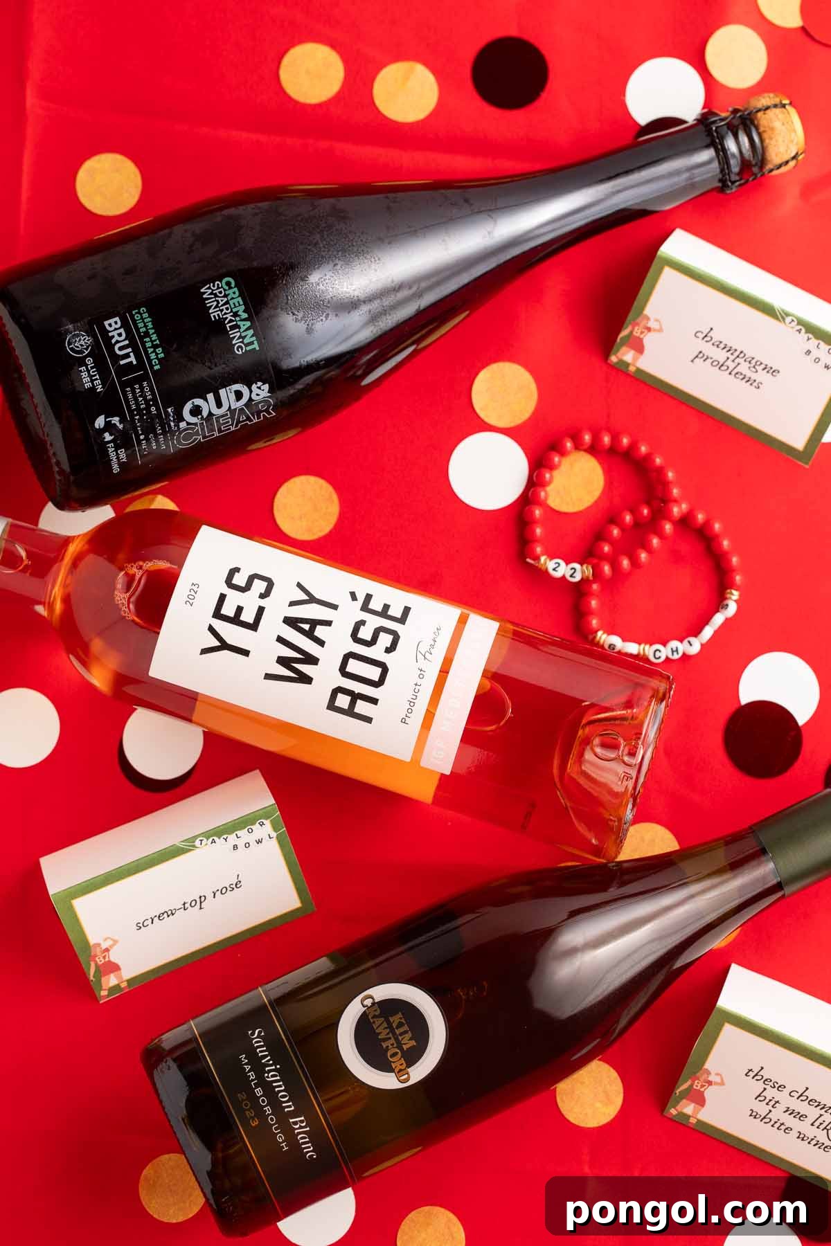 Champagne, white wine, and rosé bottles arrange on a table covered with a red table cloth, suggesting a sophisticated drink station.