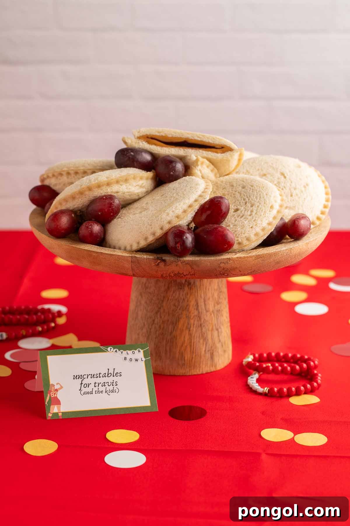 A wooden cake stand holding an arrangement of peanut butter and grape jelly Uncrustables, a nostalgic treat.