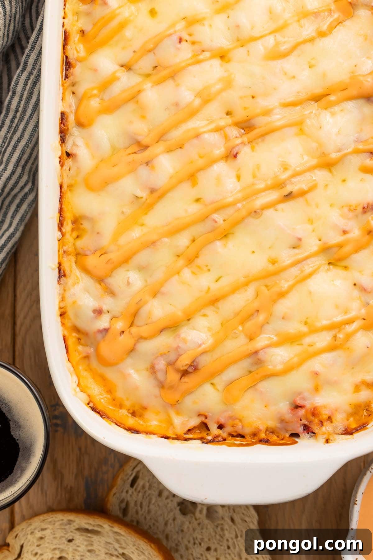 A close-up view of the corner of a bubbling Reuben casserole in a baking dish, showcasing the melted Swiss cheese and well-defined layers.