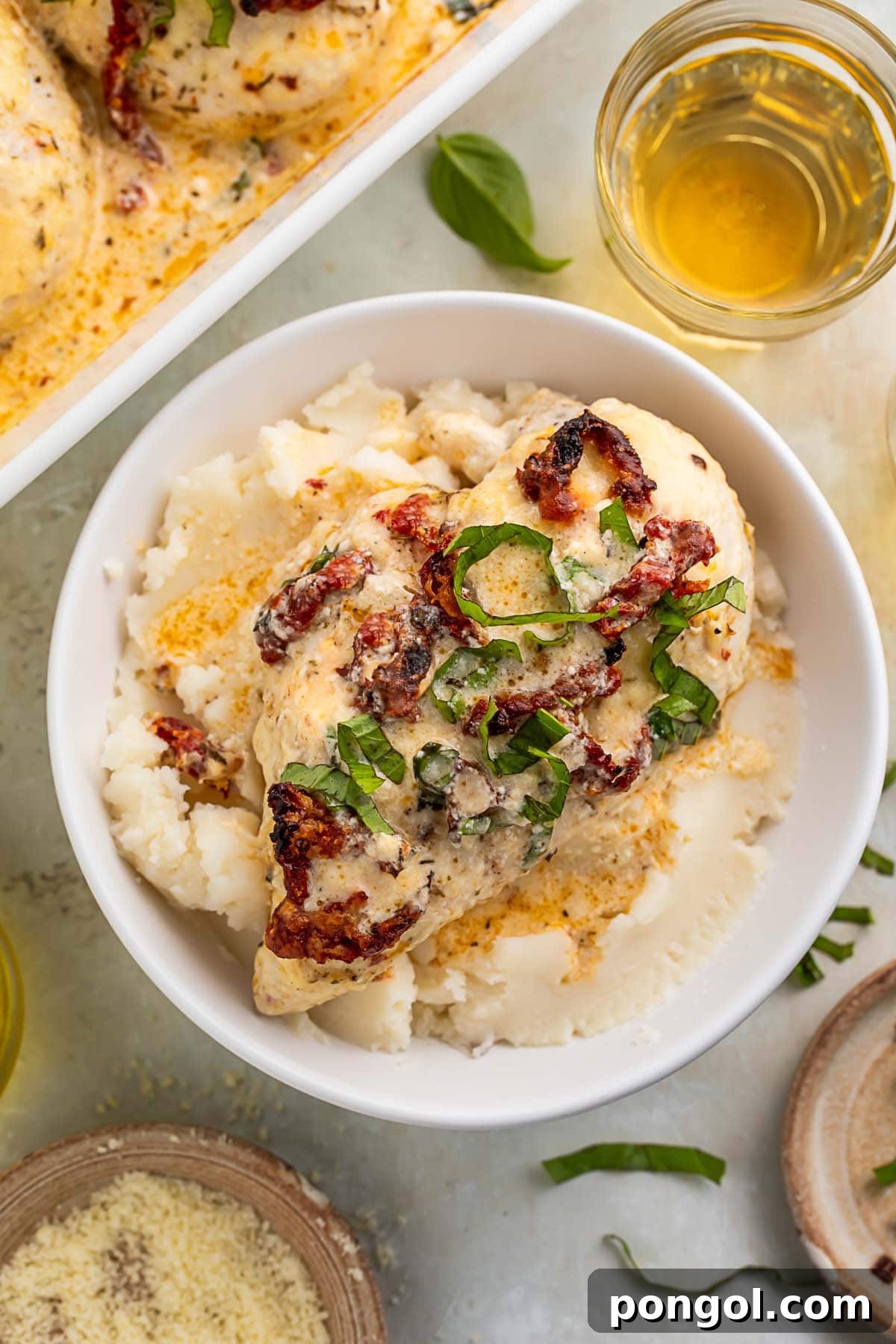 A bowl of creamy marry me chicken casserole on a bed of mashed potatoes, ready to be served.