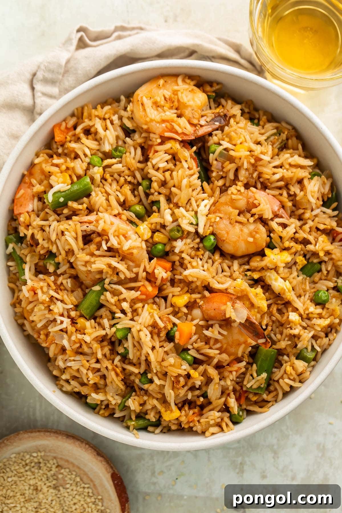 Golden Shrimp Fried Rice Feast 4 A large white bowl holding fully-prepared shrimp fried rice with large juicy shrimp, green beans, and peas littered throughout.