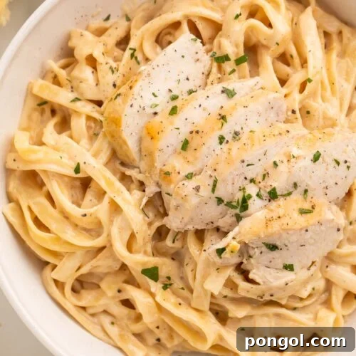 Close-up of Instant Pot chicken alfredo in a large white bowl on a table.