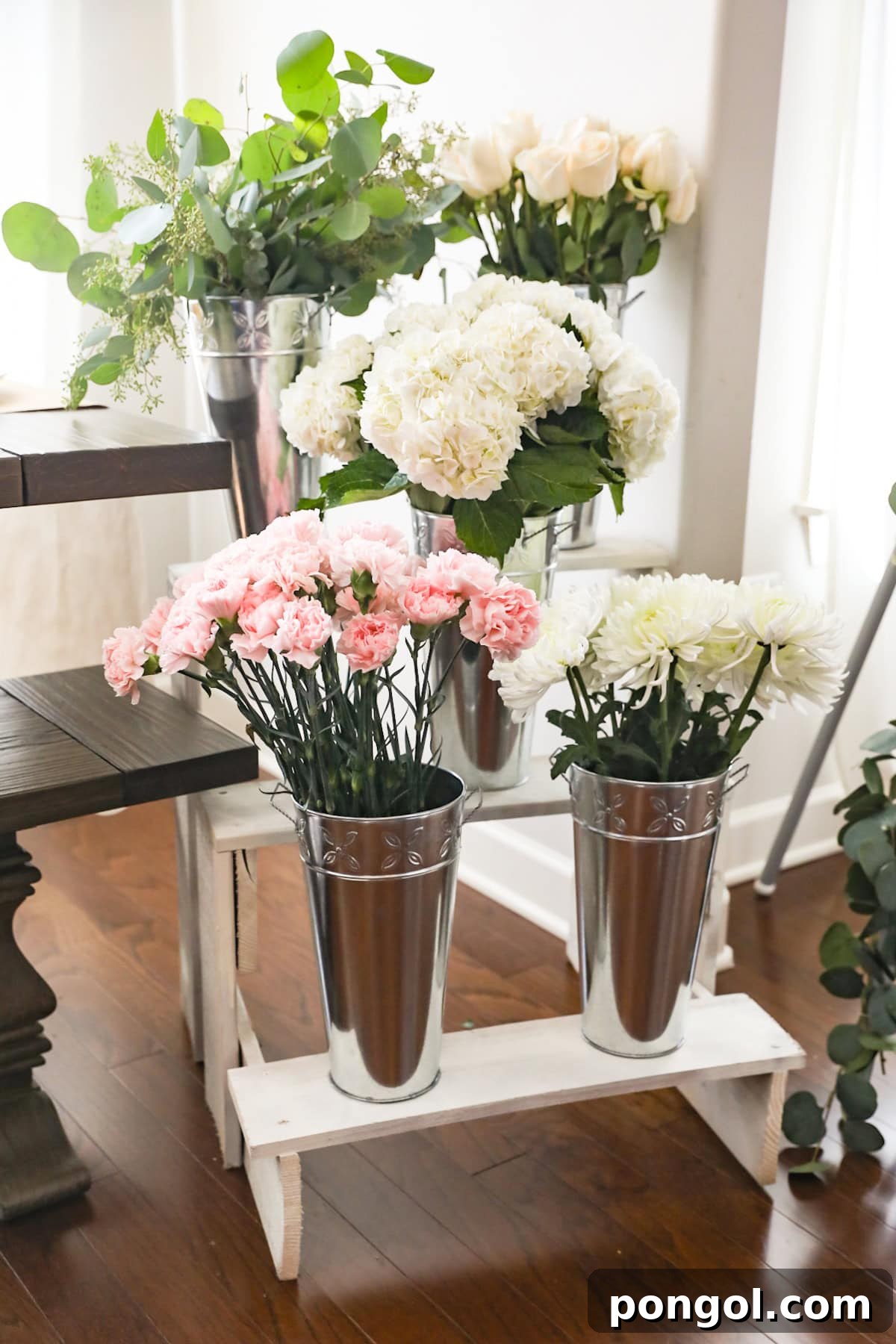 A French-style flower stall set-up with 5 types of flowers and greenery on a tiered stand.