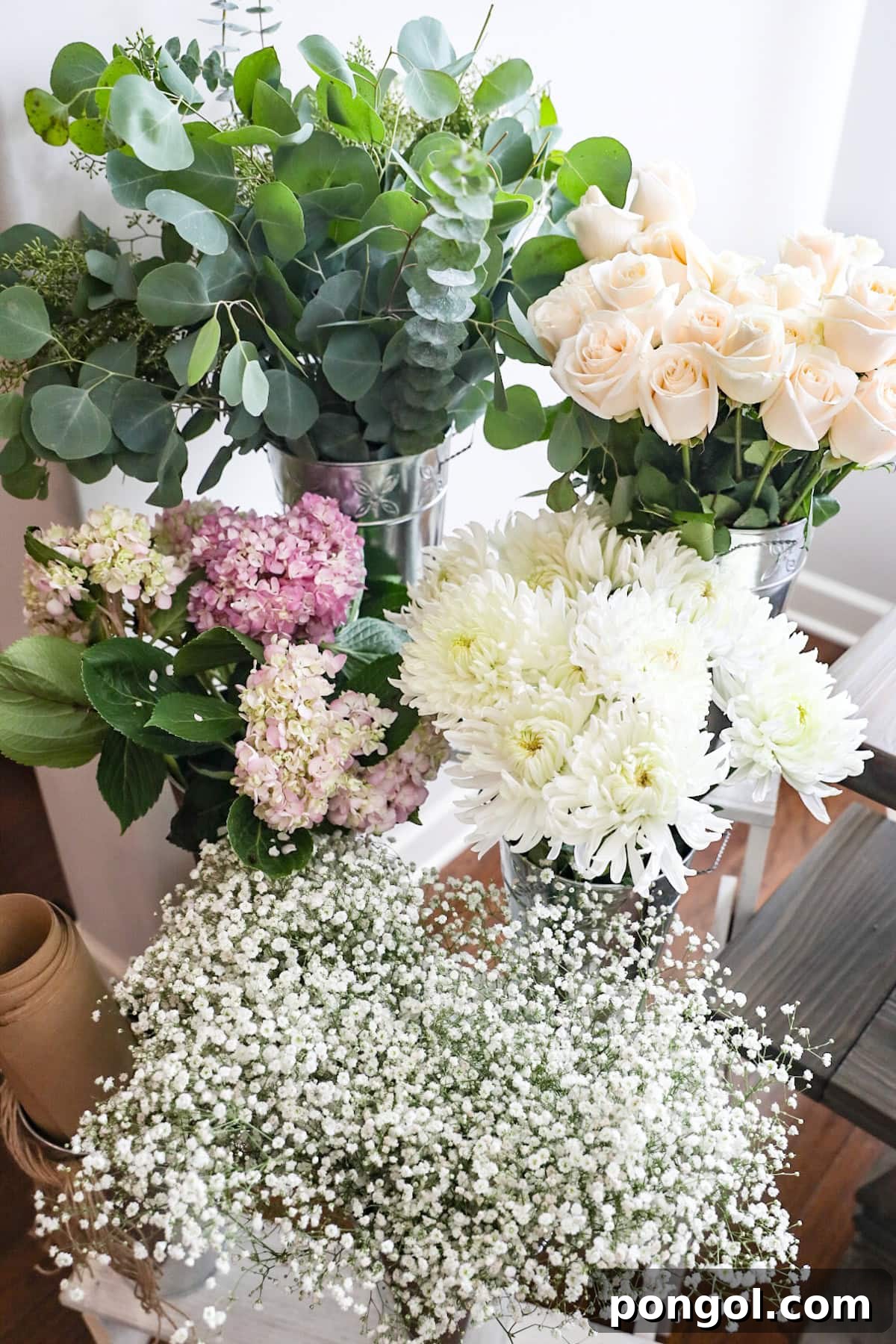 A French-style flower stall set-up with 5 types of flowers and greenery on a tiered stand.