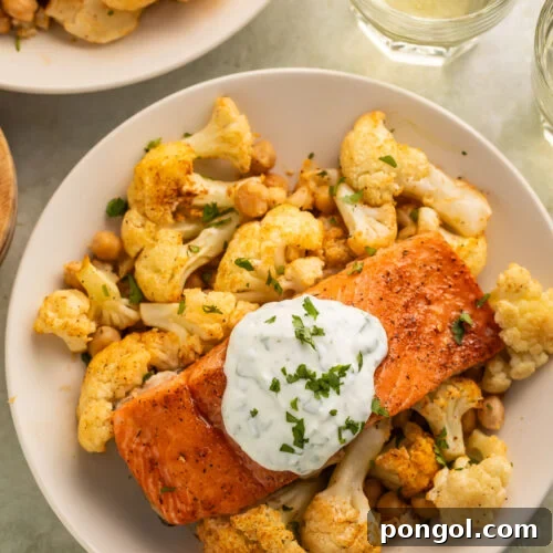 A bowl of sheet pan salmon and cauliflower with hot honey and yogurt sauce, ready to be served.