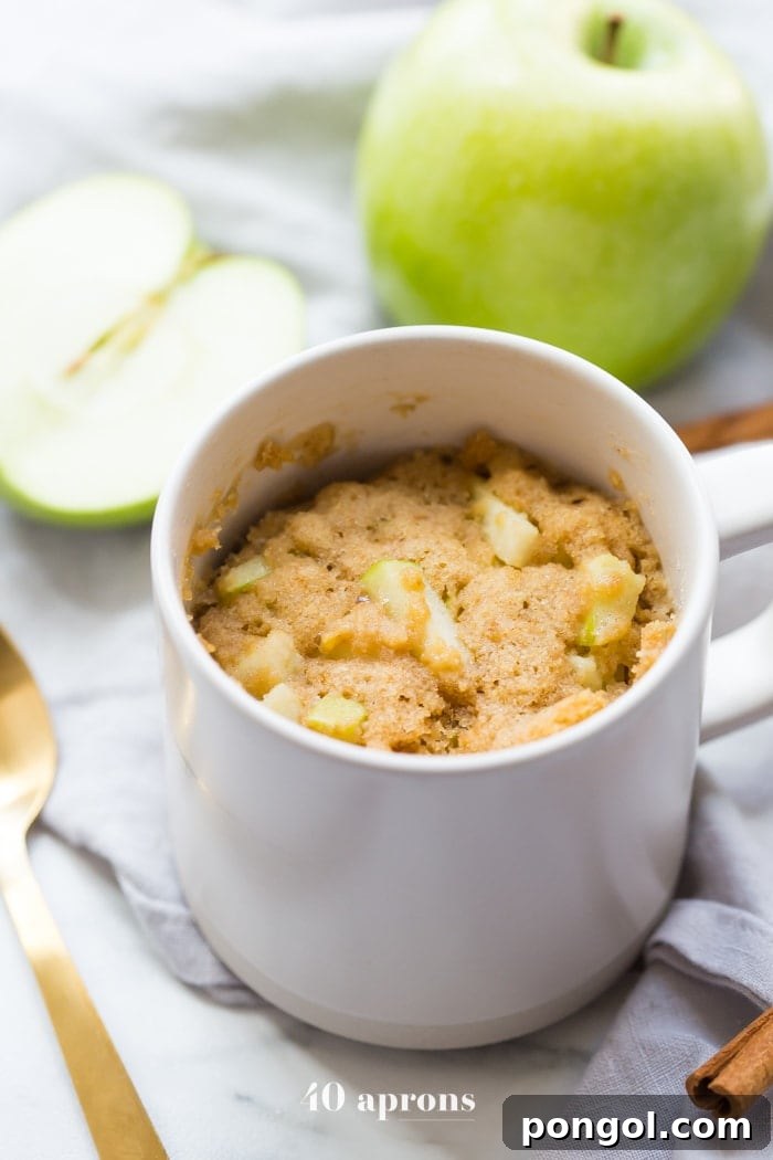 Paleo Caramel Apple Mug Cake 4 A close-up of the delightful Paleo Caramel Apple Microwave Cake, showcasing its fluffy yet moist texture, speckled with green apple chunks.