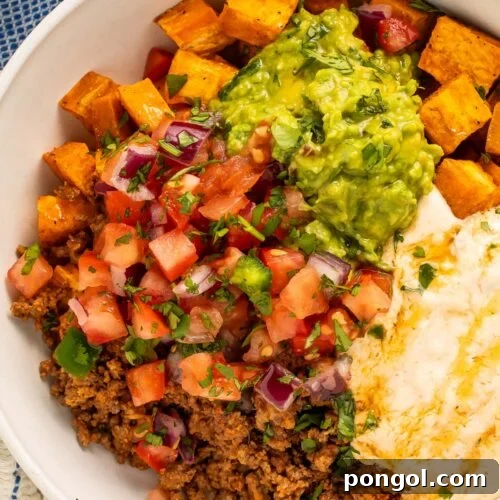 Close-up photo of a Southwest Ground Beef Bowl with Cottage Cheese Queso on a table, highlighting its fresh ingredients and inviting texture.