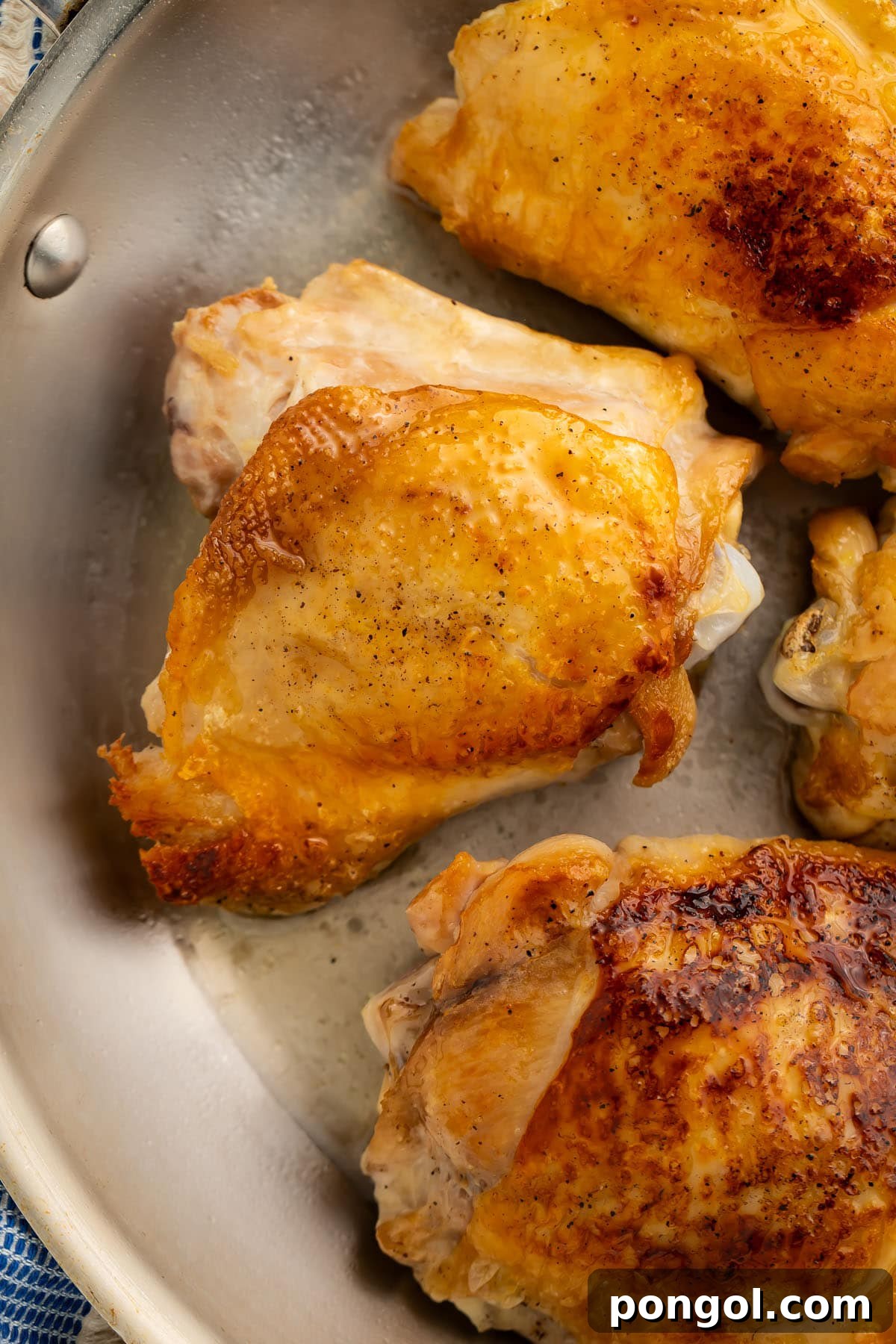 Golden-Crisp Juicy Chicken Thighs 2 Perfect crispy chicken thighs in a large skillet, glistening with golden-brown skin, ready to be served.