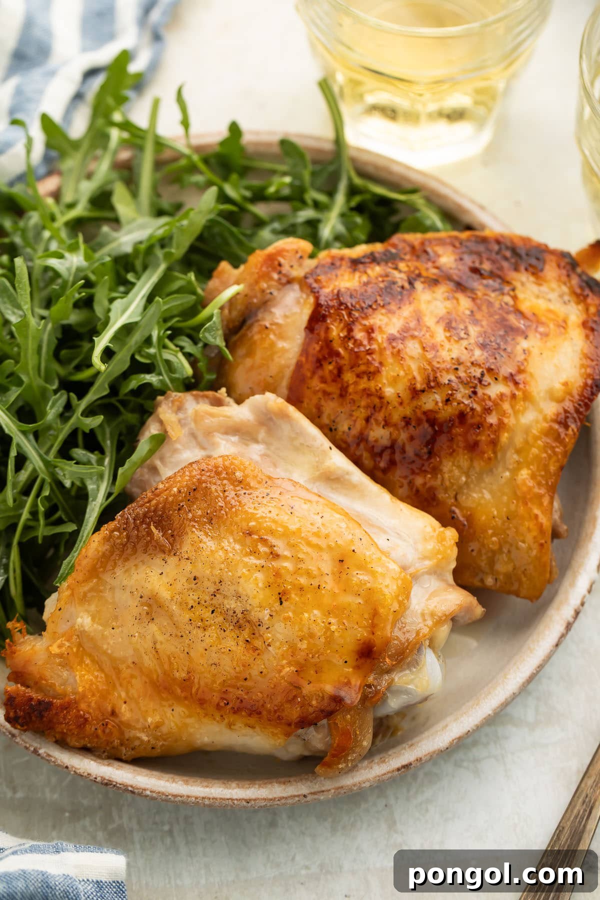 Golden-Crisp Juicy Chicken Thighs 3 Two perfect crispy chicken thighs plated with a fresh, vibrant leafy green side salad, ready for a delicious meal.