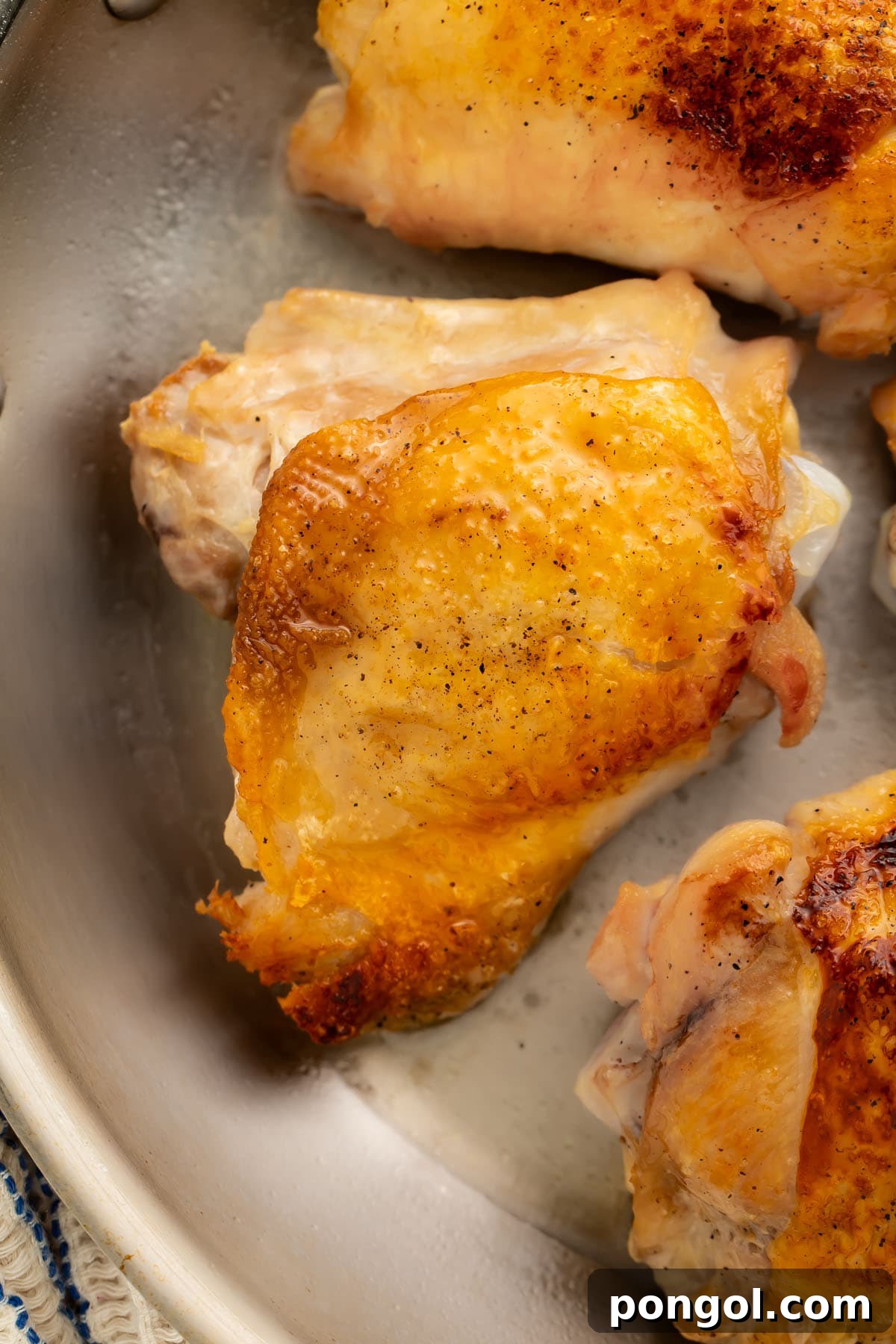 Golden-Crisp Juicy Chicken Thighs 4 Close-up of perfect crispy chicken thighs in a large cast-iron skillet, showcasing their golden-brown skin and succulent appearance.