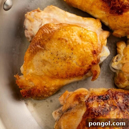 Perfect crispy chicken thighs in a large skillet, ready to be removed and served.
